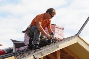 Homeowner inspecting roof shingles and clearing leaves from a gutter before a summer storm.